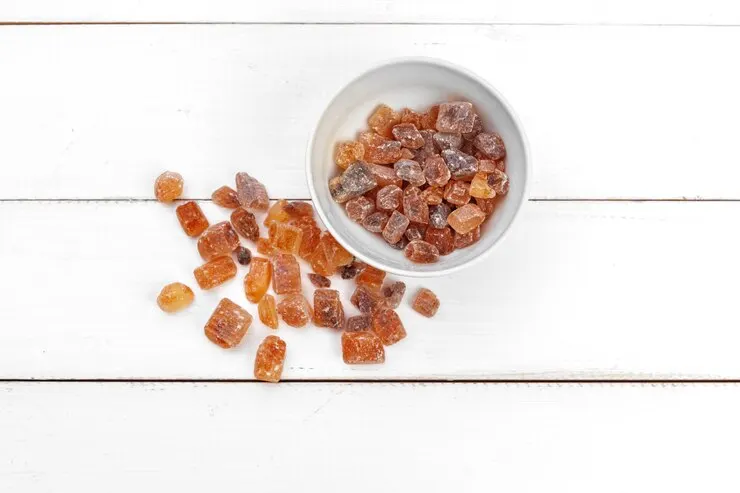 Amber-coloured dried peach gum resin crystals in a bowl beside a soaked, swollen batch