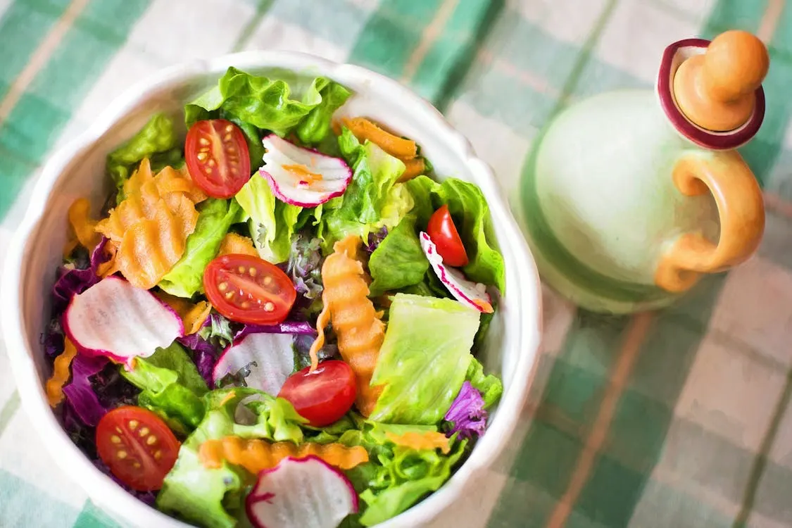A vibrant bowl of fresh salad featuring ripe tomatoes, crisp lettuce, and a variety of colourful vegetables. Perfect for a healthy meal.