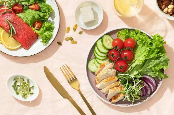 Top view two plates with keto diet food golden fork knife