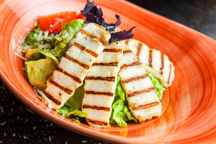 Grilled chicken crispy rice salad featuring lettuce and tomatoes served on a vibrant orange plate, showcasing a colourful and healthy meal.