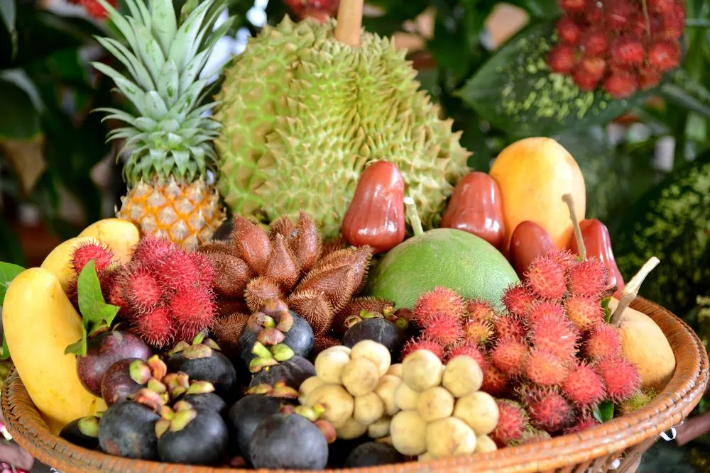 A market display of spiky tropical fruits including durian, rambutan and lychee