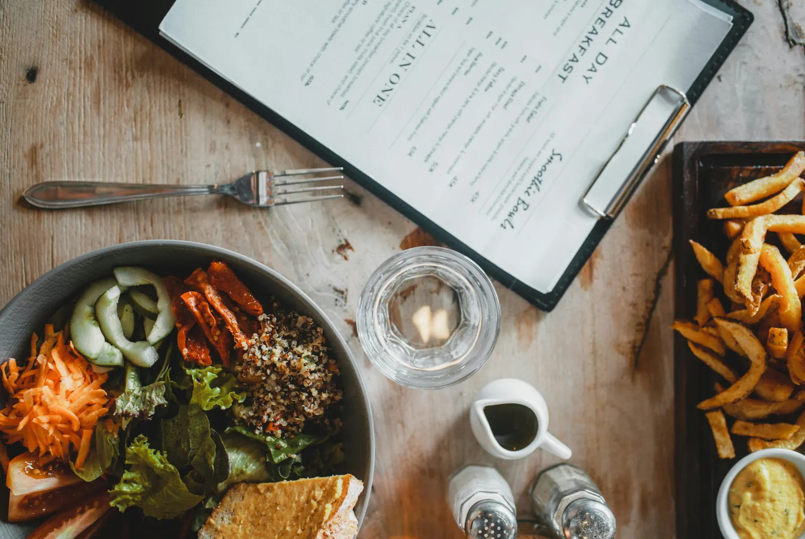  A table featuring a bowl of fresh salad alongside a serving of crispy fries, highlighting vegan-friendly dining options.