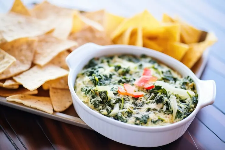 Fresh spinach artichoke dip white bowl with tortilla chips
