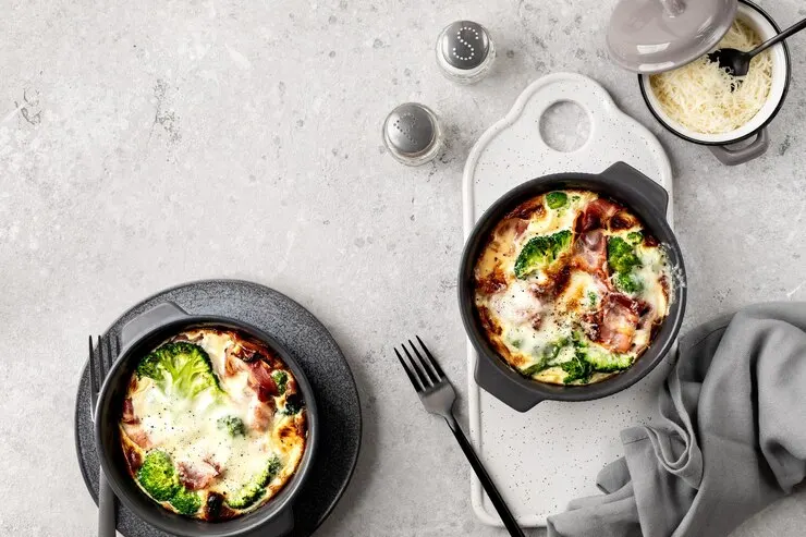 Two pans of individual broccoli wild rice casserole on a table, elegantly set with a napkin for a Valentine's Day celebration. 