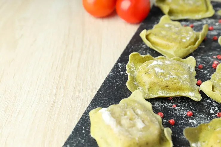  A plate of vegan kale and sweet potato ravioli garnished with fresh tomatoes, perfect for a romantic Valentine's meal.