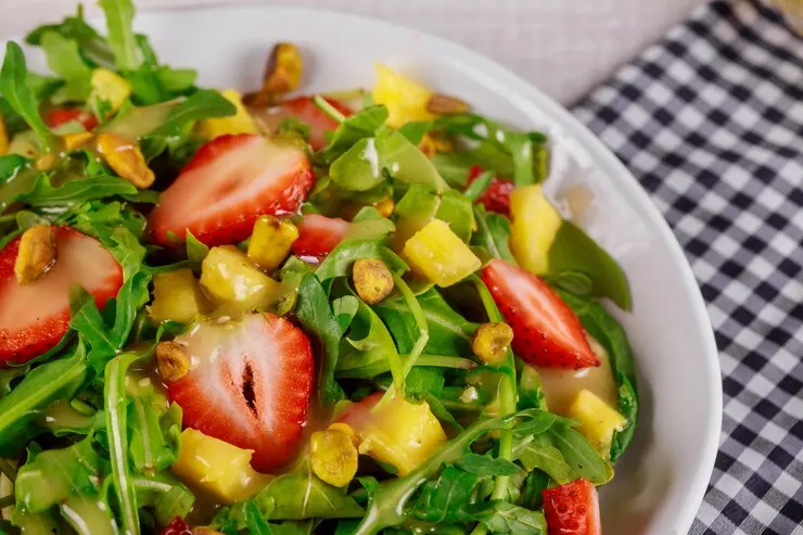 Green fresh salad with arugula strawberries mango pistachios