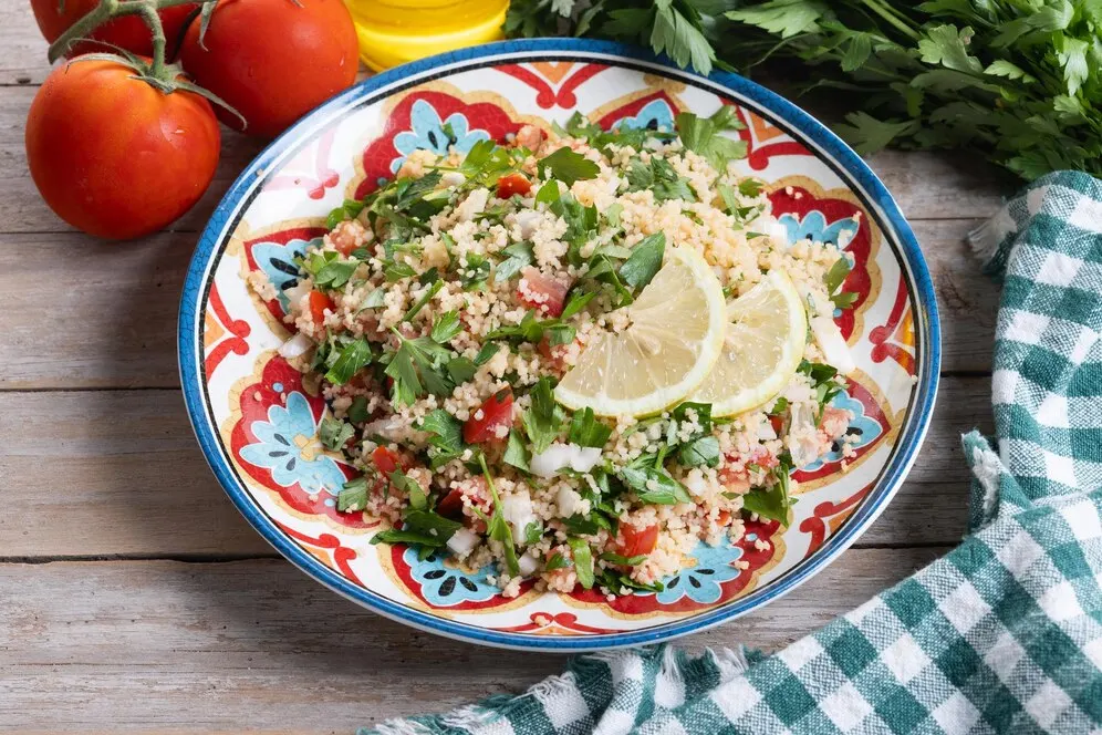 Mediterranean quinoa bowl with chickpeas, cucumber, tomato and lemon dressing on a wooden table