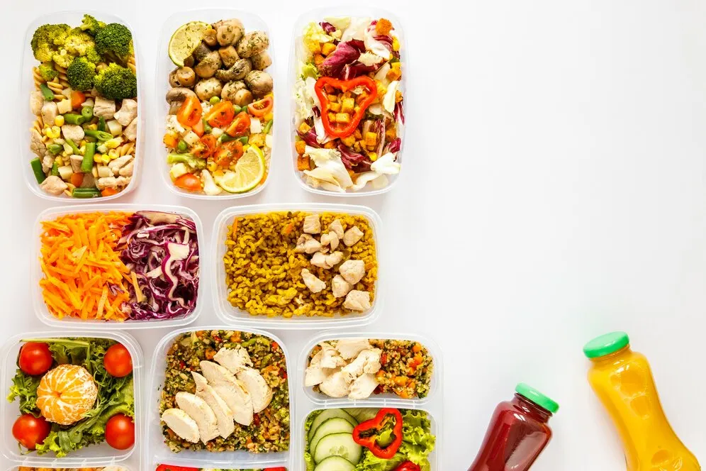 Four vegan meal prep bowls in glass containers, filled with quinoa, chickpeas, roast vegetables and fresh herbs