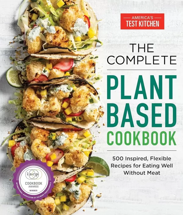 plant-based-cookbook.webp Cover of "The Complete Plant-Based Cookbook" by America's Test Kitchen. It showcases tacos brimming with vegetables, a purple award seal from the ICAP Cookbook Awards, and the subtitle: "500 Inspired, Flexible Recipes for Eating Well Without Meat." A true import of culinary innovation.