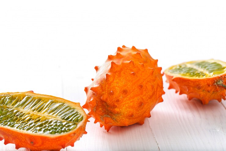 A close-up shot of a kiwano, also known as horned melon, isolated against a plain background. The fruit's vibrant orange skin with its distinctive spiky texture is clearly visible, highlighting its unique and exotic appearance.