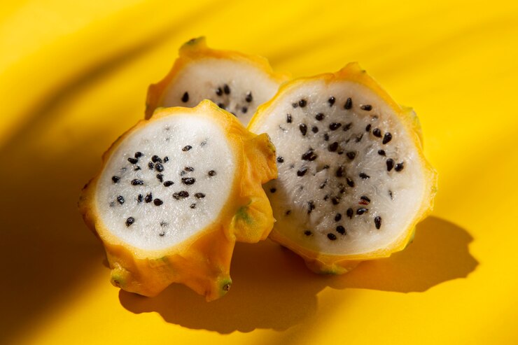 A composition of delicious exotic yellow dragon fruit arranged on a white surface. The vibrant yellow color and unique spiky texture of the dragon fruit are highlighted, creating an eye-catching and appealing visual.