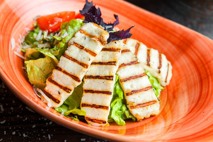 Grilled chicken crispy rice salad featuring lettuce and tomatoes served on a vibrant orange plate, showcasing a colorful and healthy meal.
