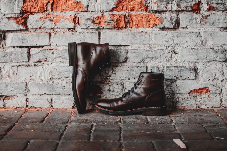 Trendy brown vegan leather boots displayed on a brick wall, highlighting contemporary fashion in sustainable footwear.