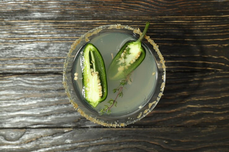 A glass of jalapeno juice garnished with two fresh jalapenos, showcasing a vibrant and spicy homemade beverage.