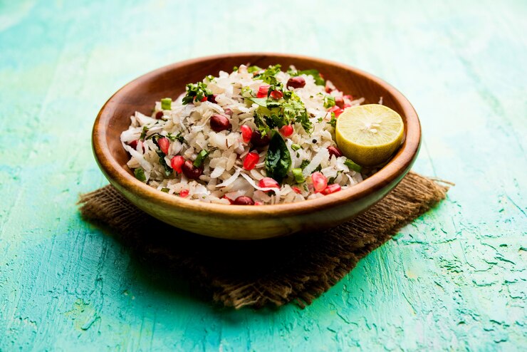A vibrant Indian rice salad featuring pomegranate and lemon, elegantly displayed on a wooden table, by Sivan’s Kitchen.