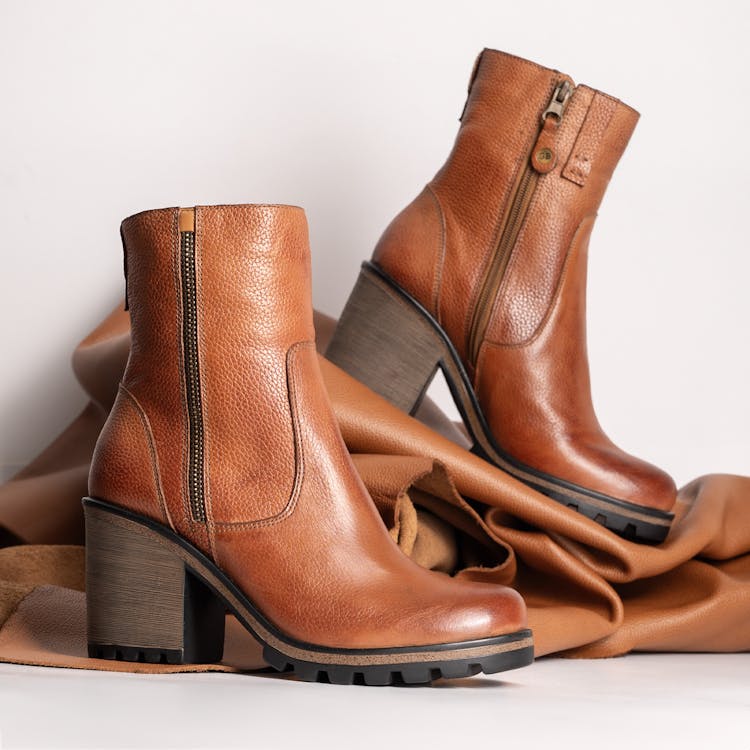  A pair of stylish brown vegan leather boots featuring a convenient zipper for easy wear.