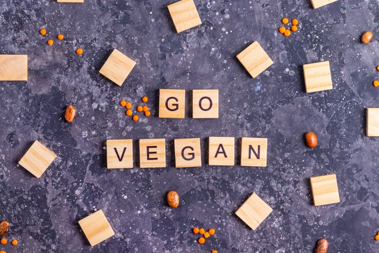 The phrase "go vegan" formed by wooden blocks on a dark background, emphasizing plant-based alternatives to animal products.