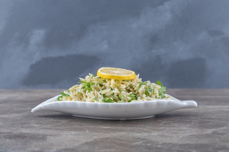 A white dish featuring Kale Junkie’s Crispy Rice Salad, garnished with lemon, elegantly placed on a table.