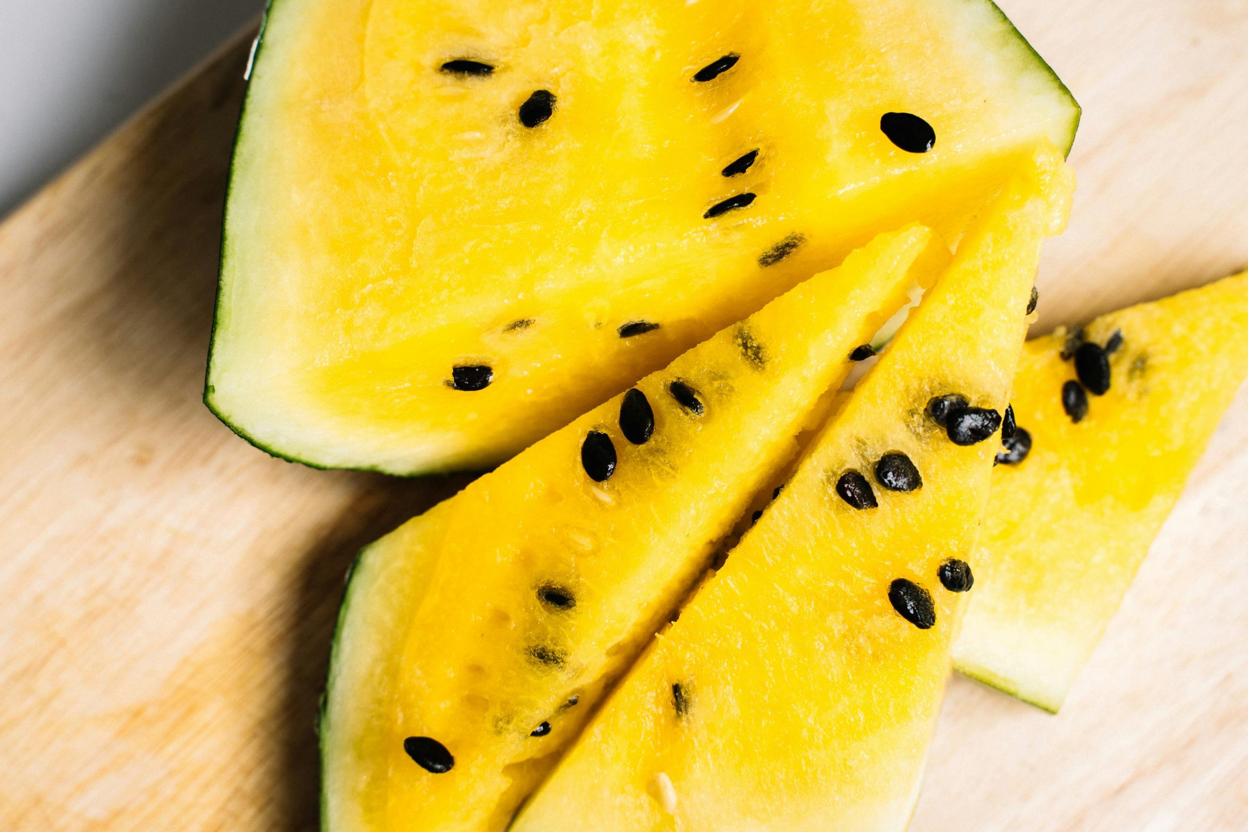 A slice of yellow melon showcasing its seeds on top, highlighting the vibrant yellow color of the watermelon inside.