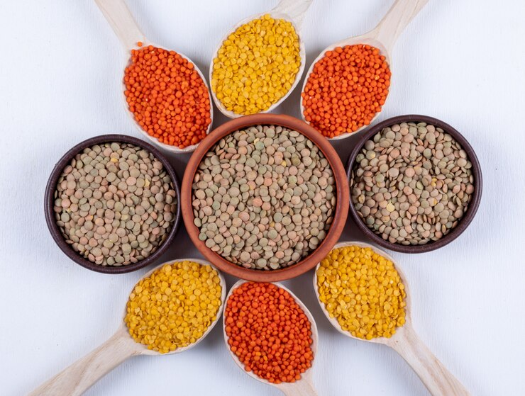 Dried lentils in bowls with spoons, set against a white background, perfect for a quick vegan lentil bolognese recipe.