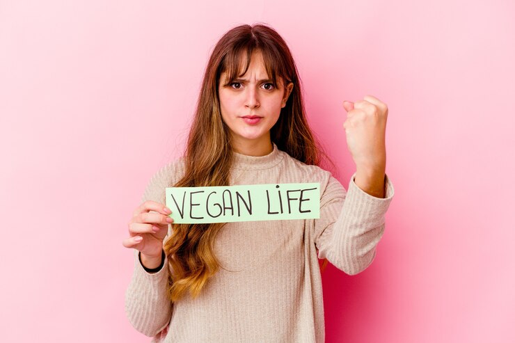 A passionate vegan activist holds a sign that states "Vegan Life," advocating for plant-based living.