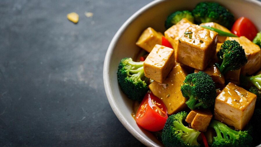 A bowl of stir-fried veggies & tofu drizzled with sauce, perfect for a romantic Valentine's Day meal for two.