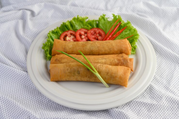 Three vegan spring rolls elegantly arranged on a white plate, perfect for a memorable Valentine's Day celebration.