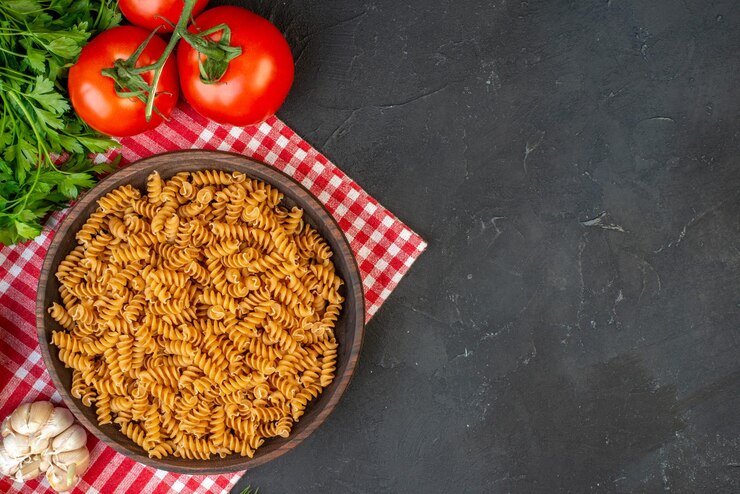 A vibrant vegan tomato fusilli pasta adorned with fresh herbs, elegantly presented on a black table for Valentine's Day.