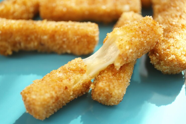 Cheesy vegan mozzarella sticks cut into pieces, elegantly arranged on a blue plate for a festive Valentine's Day treat.