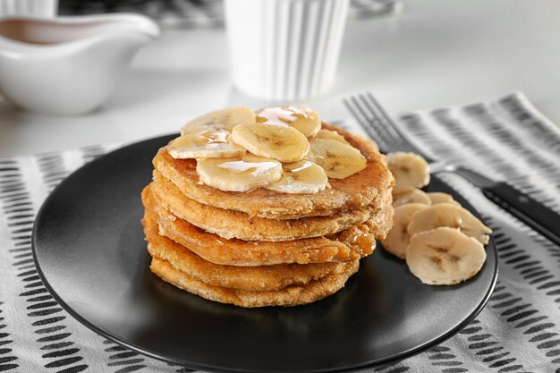 A stack of vegan banana oat pancakes topped with fresh banana slices, showcasing a delicious breakfast option.