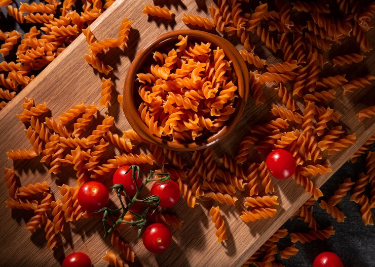 A bowl of vegan tomato fusilli pasta adorned with fresh tomatoes and cherry tomatoes, perfect for Valentine's Day.