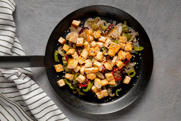 A pan filled with crispy sweet chili tofu and colorful vegetables, perfect for a Valentine's Day meal.