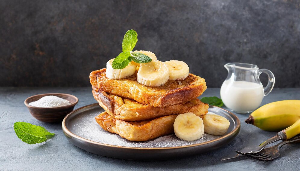 A delicious serving of banana French toast topped with maple syrup and fresh mint, perfect for a romantic breakfast.