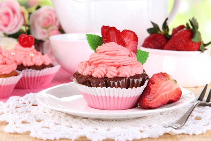 A white plate holds delightful vegan strawberry cupcakes topped with pink frosting, perfect for Valentine's Day celebrations.