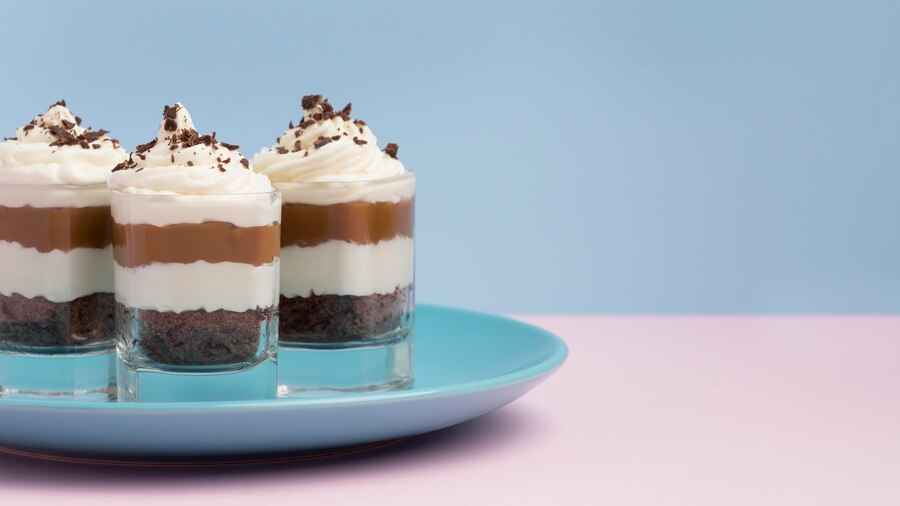 Three dessert shots of date-sweetened chocolate panna cotta elegantly arranged on a blue plate for Valentine's Day.
