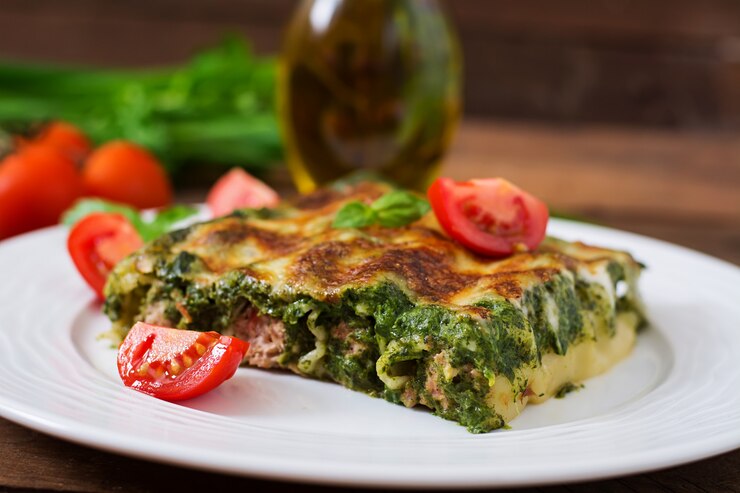 A slice of vegan lasagna verde featuring layers of spinach and tomatoes, perfect for a romantic Valentine's Day meal.