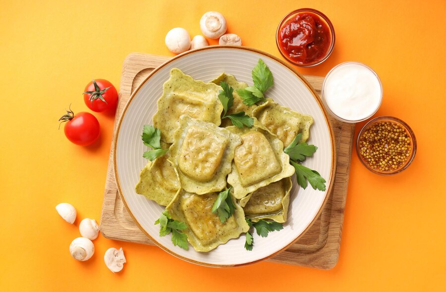 A plate of vegan kale and sweet potato ravioli topped with colorful vegetables and a rich sauce, perfect for Valentine's Day.