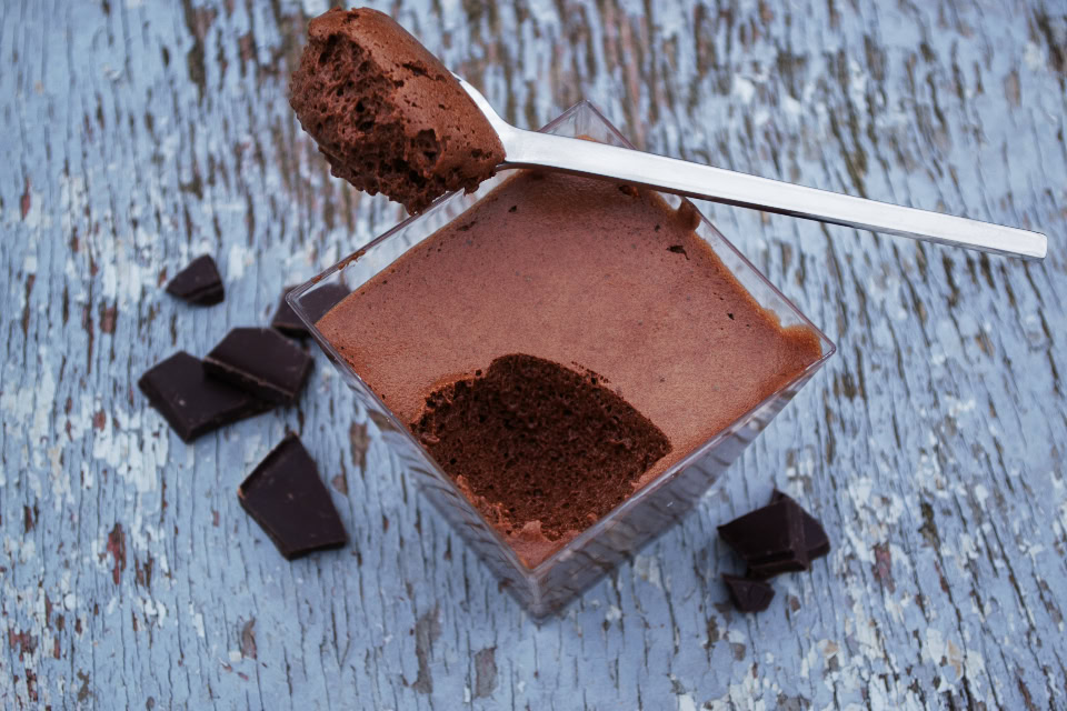 A spoon rests in a glass filled with Date-Sweetened Chocolate Panna Cotta, perfect for Valentine's Day.