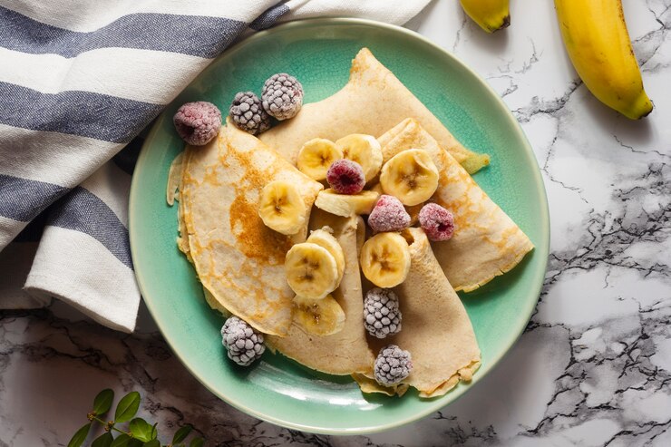 A plate of vegan Palacinky topped with fresh berries and banana slices, perfect for a Valentine's Day treat.