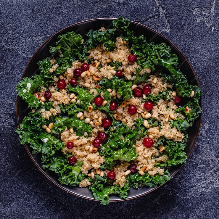 A delicious Cornucopia Kale Salad with cranberry quinoa featuring pine nuts, set against a dark backdrop, perfect for Valentine's Day.