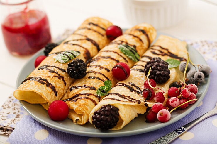 A plate of vegan Palacinky crepes topped with fresh berries and syrup, perfect for a Valentine's Day celebration.