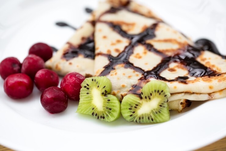 A plate of Vegan Palacinky (Czech Sweet Crepes) topped with fresh kiwi, perfect for a Valentine's Day celebration.