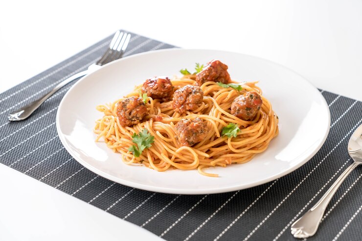 A white plate featuring vegan spaghetti topped with lentil balls, perfect for a romantic Valentine's dinner.