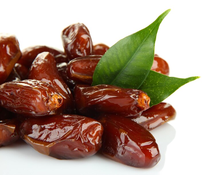 A cluster of dates with green leaves on a white background, highlighting a vegan recipe for trending pistachio-stuffed dates.