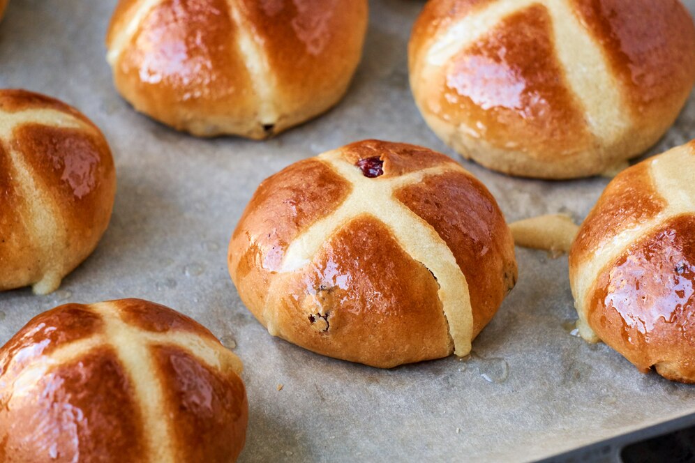 A baking sheet filled with freshly baked vegan hot cross buns, perfect for an Easter brunch celebration.