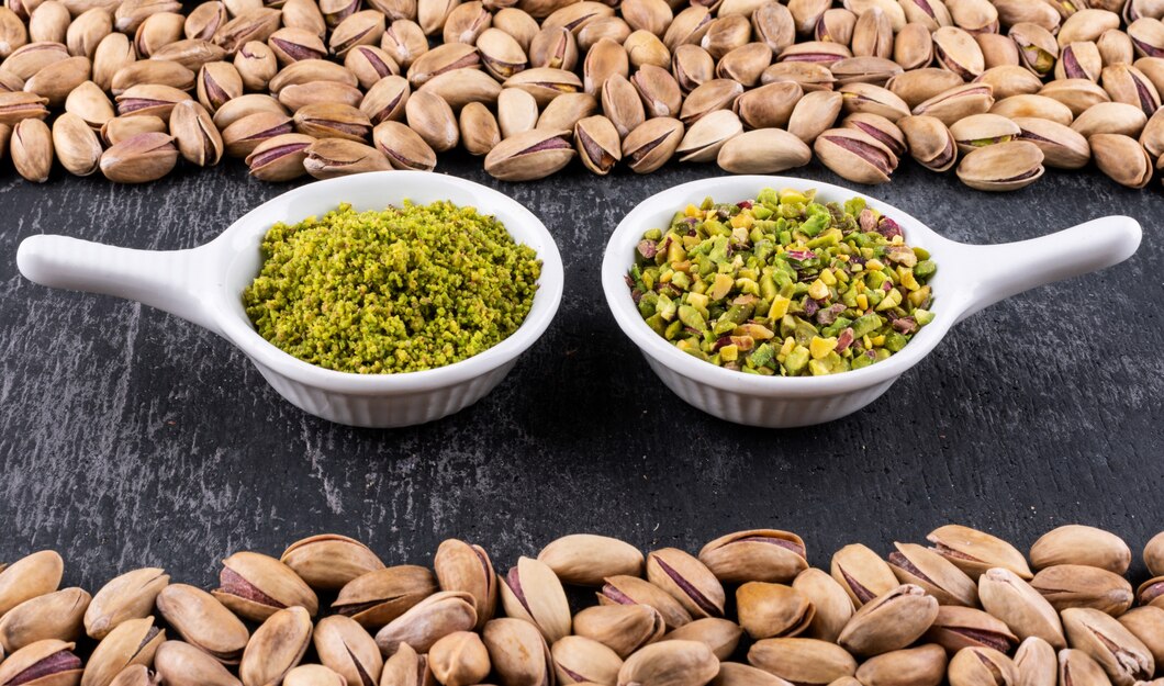 An arrangement of pistachios on a black surface, showcasing their natural hue, related to trending vegan pistachio-stuffed dates.