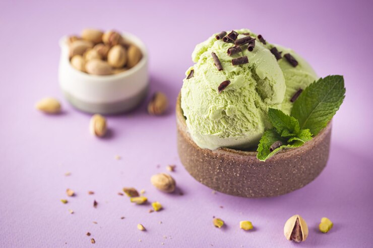 Green pistachio ice cream topped with pistachios and mint leaves, set against a vibrant purple background.