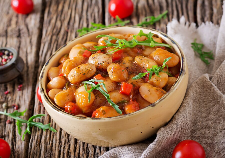 A bowl of canned butter beans with tomato sauce on a wooden table, showcasing the trending TikTok recipe "Marry Me Butter Beans."