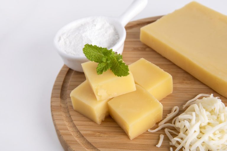 Vegan Butterkäse-style cheese cubes on a wooden board with shredded vegan cheese and potato starch, used for TikTok’s viral Butterkäse potato recipe